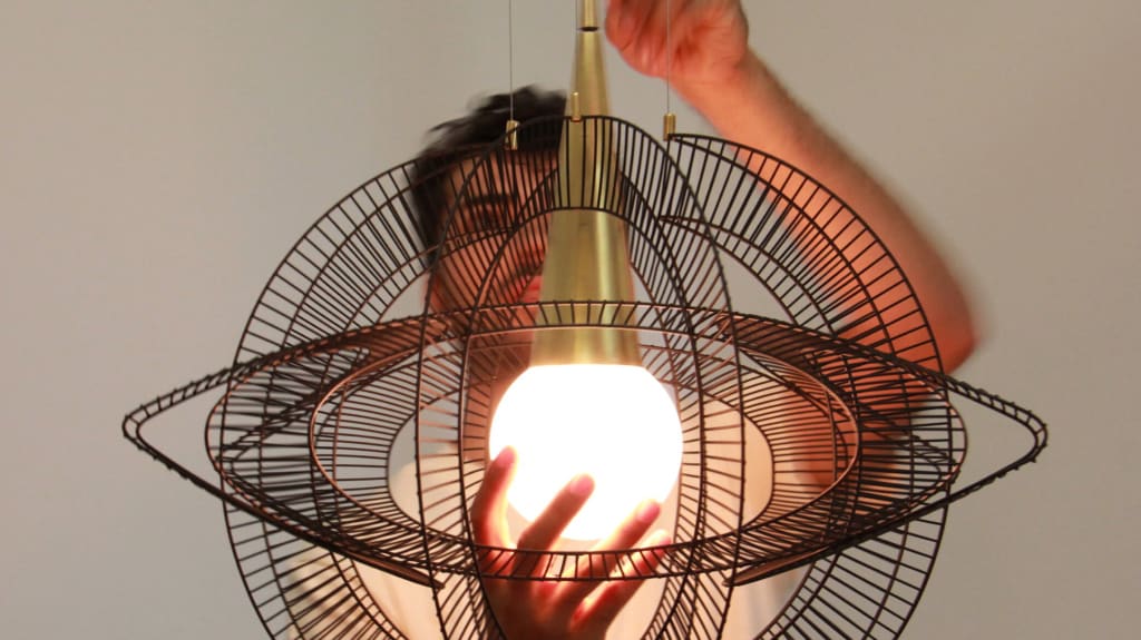 Designer of brand Studio Bottë adjusts a light fixture made with a fan grill