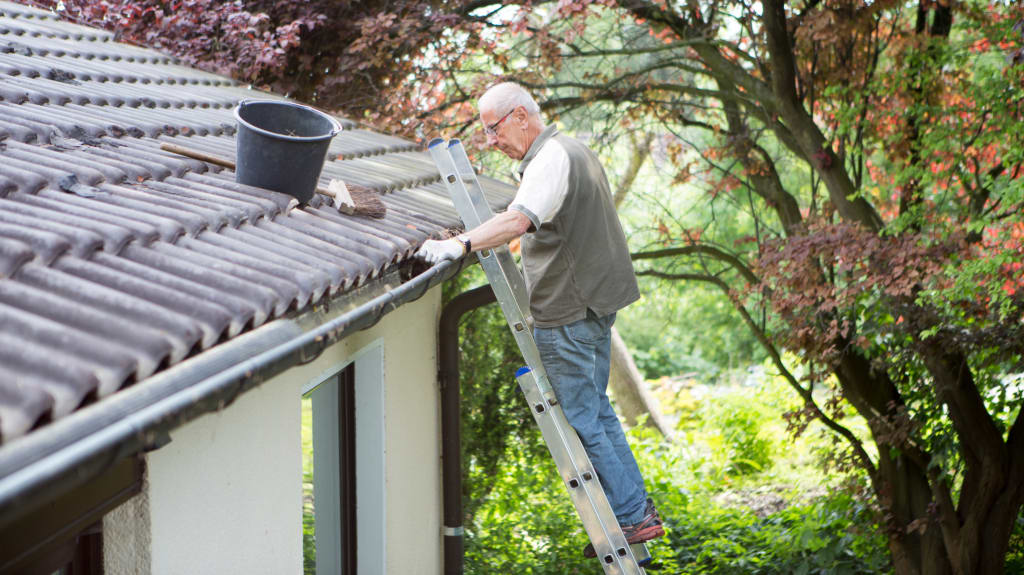 Homme sur une échelle nettoyant les gouttières
