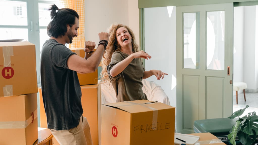 A couple dancing between boxes in their new home