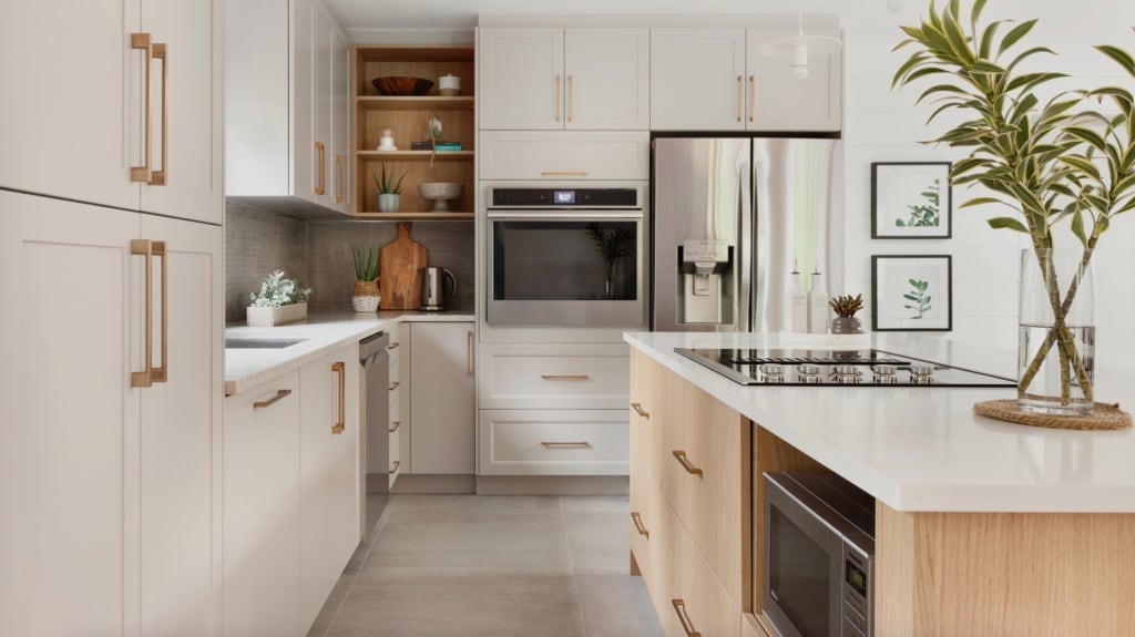 Cuisine avec armoires blanches, électroménagers en acier inoxydable, îlot avec plaque en vitrocéramique intégrée