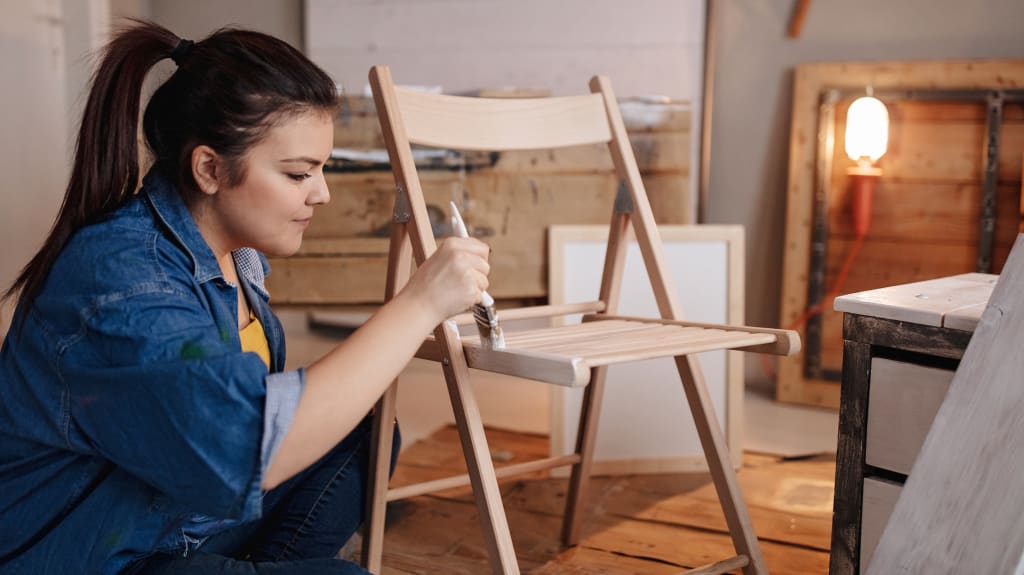 Jeune femme apposant de la peinture en aérosol sur un cadre de miroir