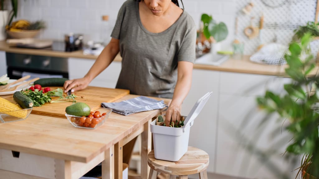 Femme plaçant ses restes de légumes dans un petit bac alloué au compost