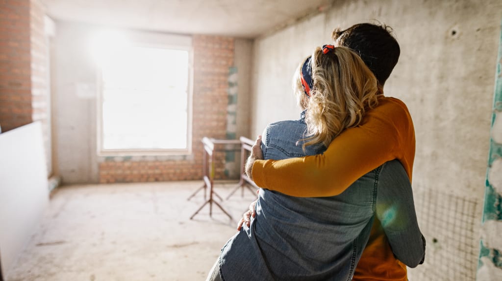Vue arrière d'un couple s'étreignant dans une pièce en cours de rénovation