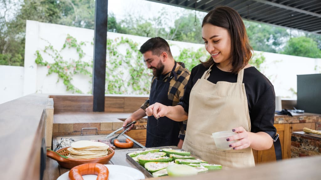 Couple en train de cuisiner dans leur cuisine extérieure