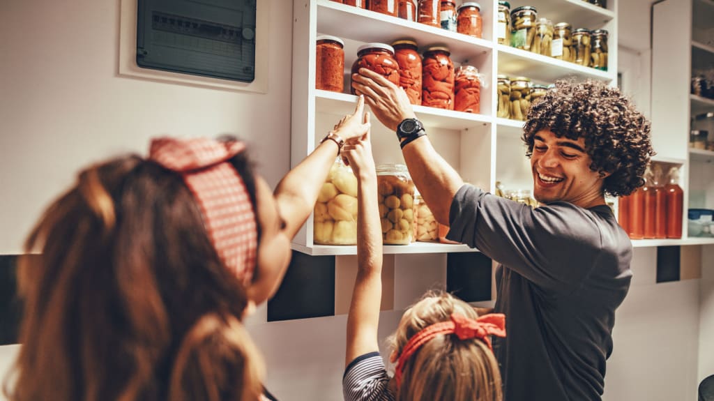 Laughing family reaching for a jar in the pantry