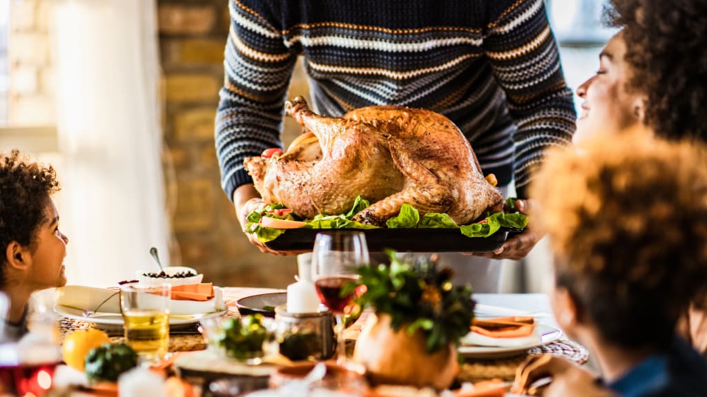 Father presenting cooked turkey to his family for Thanksgiving