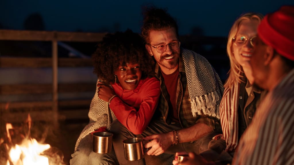 A group of friends sitting around a campfire at night