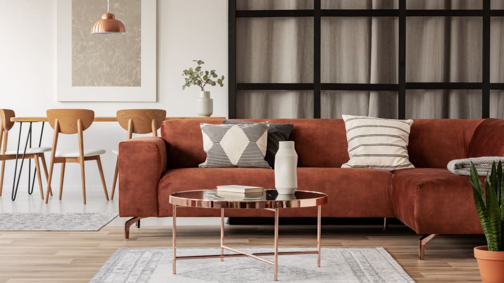 Canapé d'angle marron avec coussins à motifs dans un salon élégant avec murs à meneaux