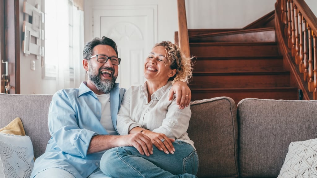 A woman and a man, seated on a sofa, are happy with the real estate support they received