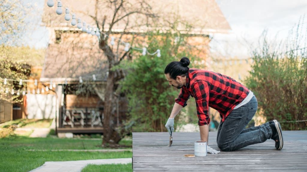 Entretien d’une terrasse en bois par une personne qui peinture