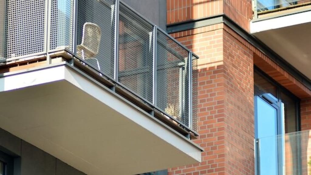 Des balcons sur la devanture d’un immeuble locatif en briques et en béton