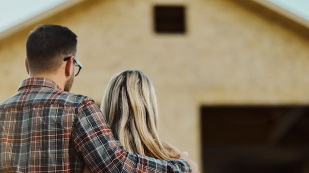 A man and a woman look at a house under construction after signing a preliminary contract
