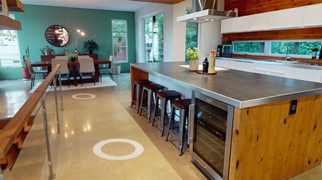 Interior of a house for sale with a view of a dining room and a kitchen featuring wood accents and a steel countertop