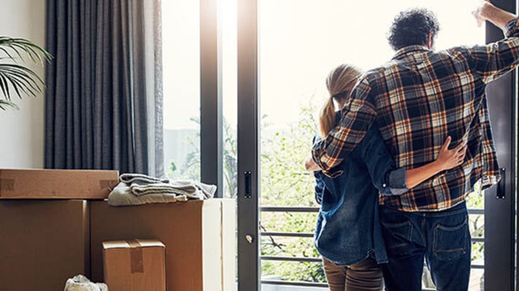 Couple embracing and looking at the view from their balcony as they prepare to move elsewhere