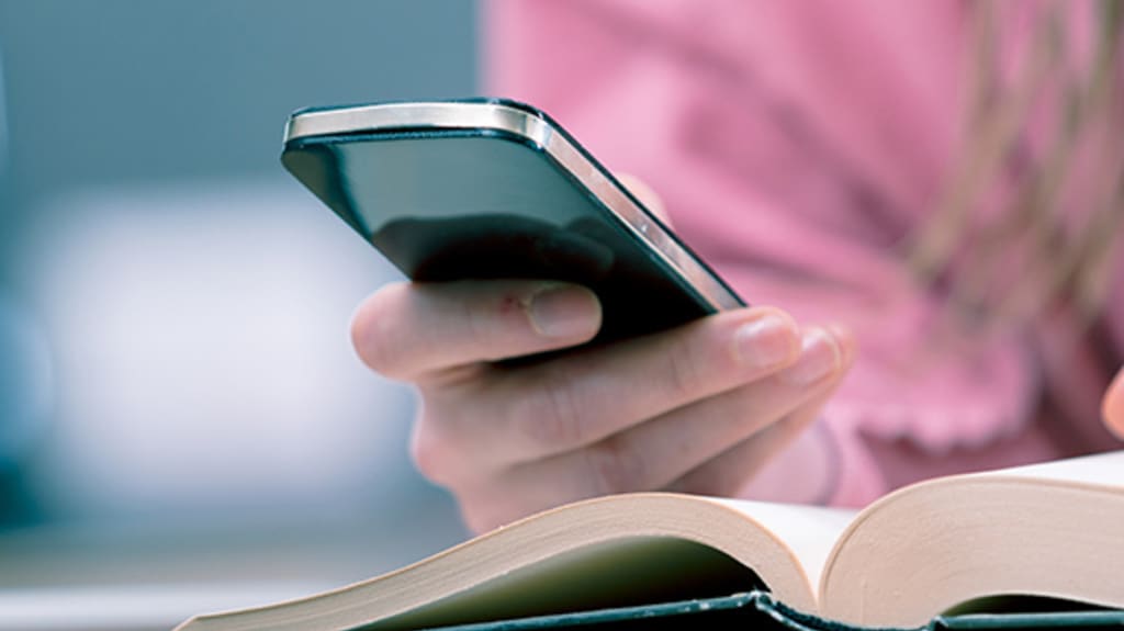 Person pointing to a page in a book and holding a cell phone to better understand mortgage loan terminology