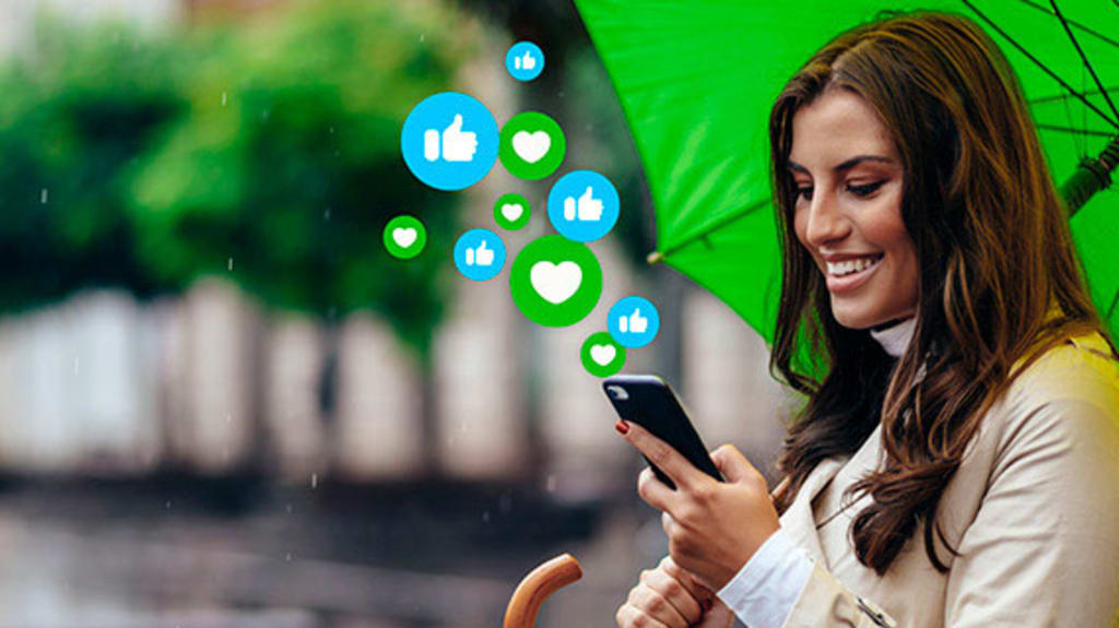 Women holding phone with social media reactions under a green umbrella