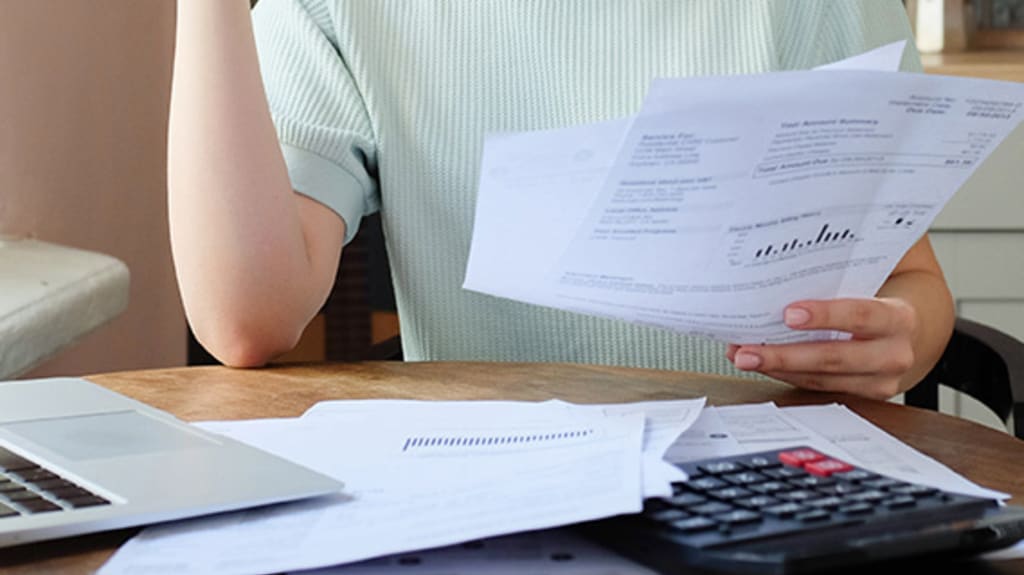 Person with a stack of papers in their hands and in front of them calculating expenses to transition from renter to homeowner