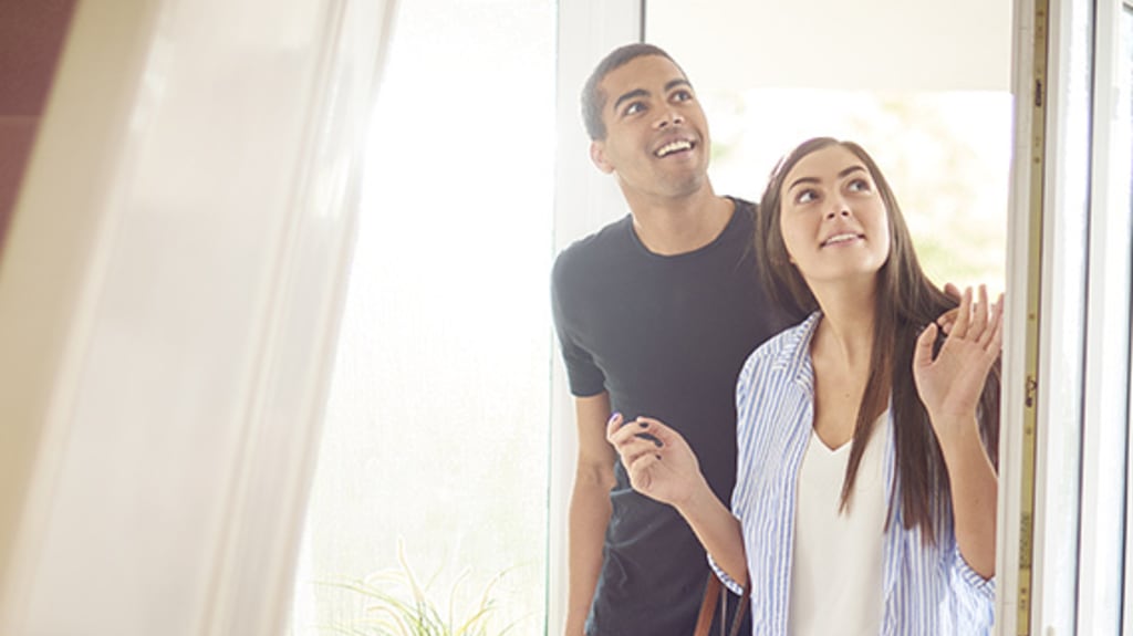 Couple qui entre dans une maison pour une visite libre et qui regarde tout autour