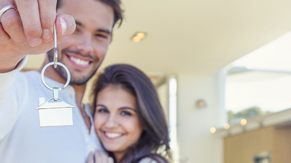 Smiling couple looking at the camera holding a key with a property-shaped keychain