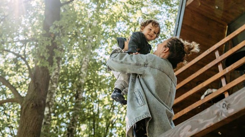 Mère et fils devant chalet situé en forêt