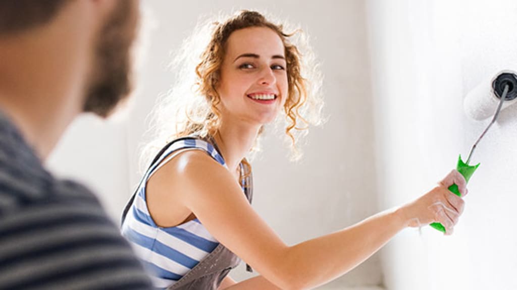Couple souriant peinturant les murs de leur appartement