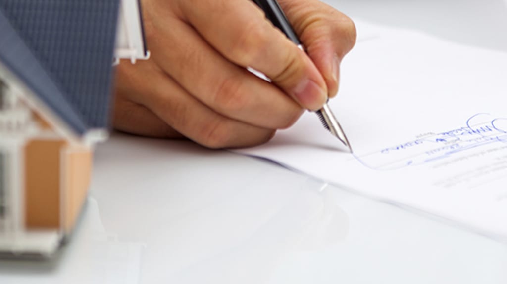 Professionnel qui signe un document nécessaire pour la vente d’une maison