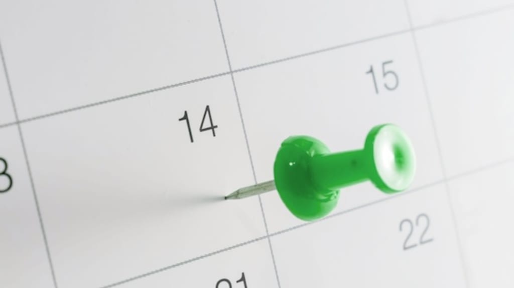 Gros plan sur un calendrier papier et des punaises dans un carnet