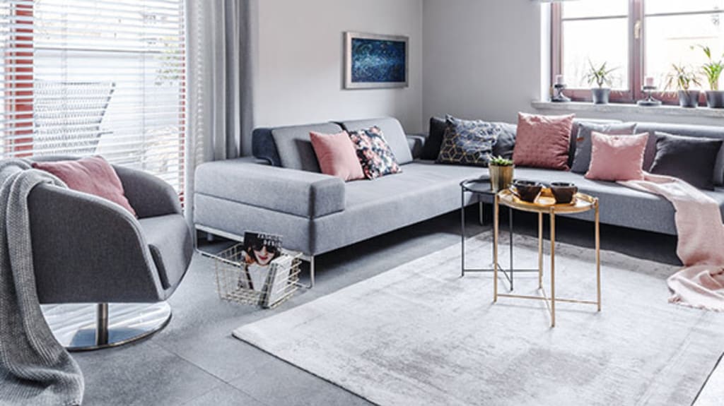 Bright living room with a metal coffee table, light gray rug, gray sofas, and pink cushions