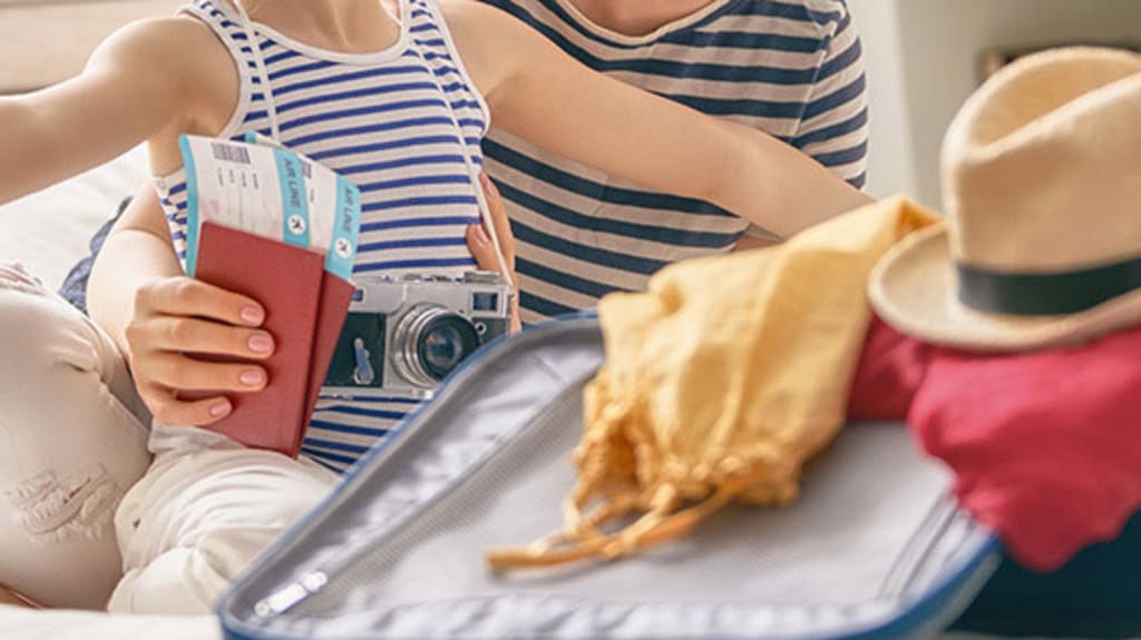 Mère qui tient son enfant et des passeports sur un lit avec valise débordant d'accessoires pour des vacances