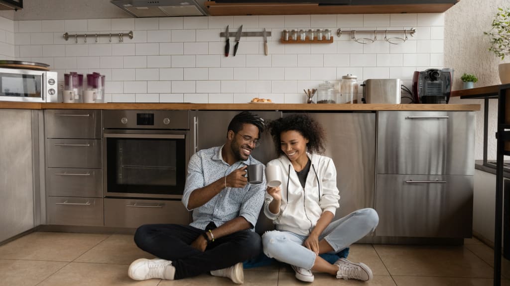 Couple assis sur le plancher de leur cuisine fraichement rénovée