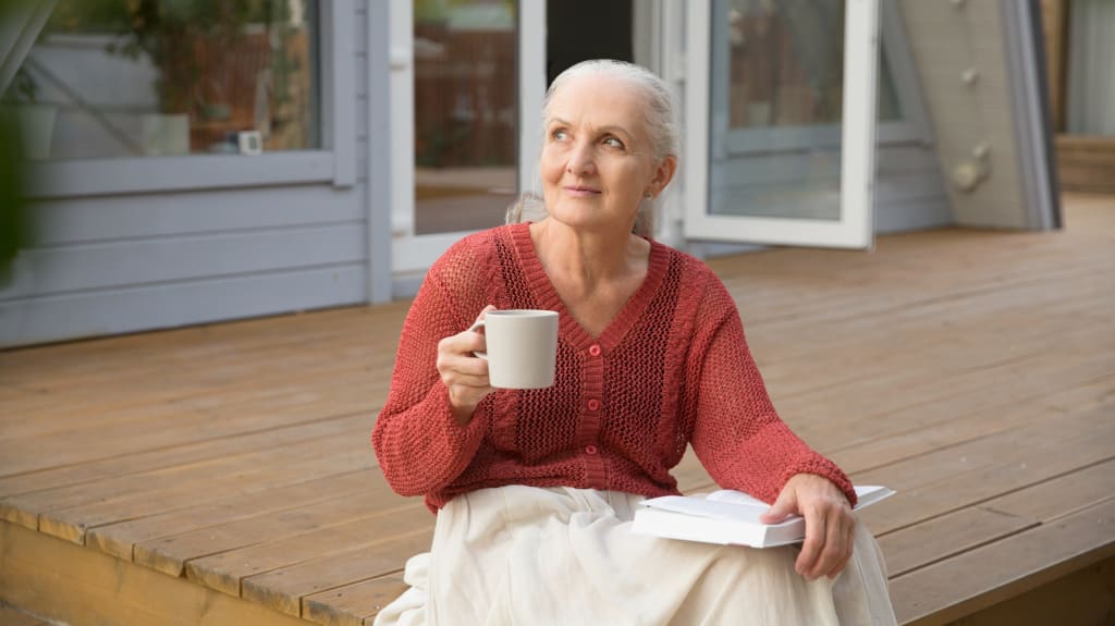 Femme assise avec une tasse de café, regardant à l'extérieur