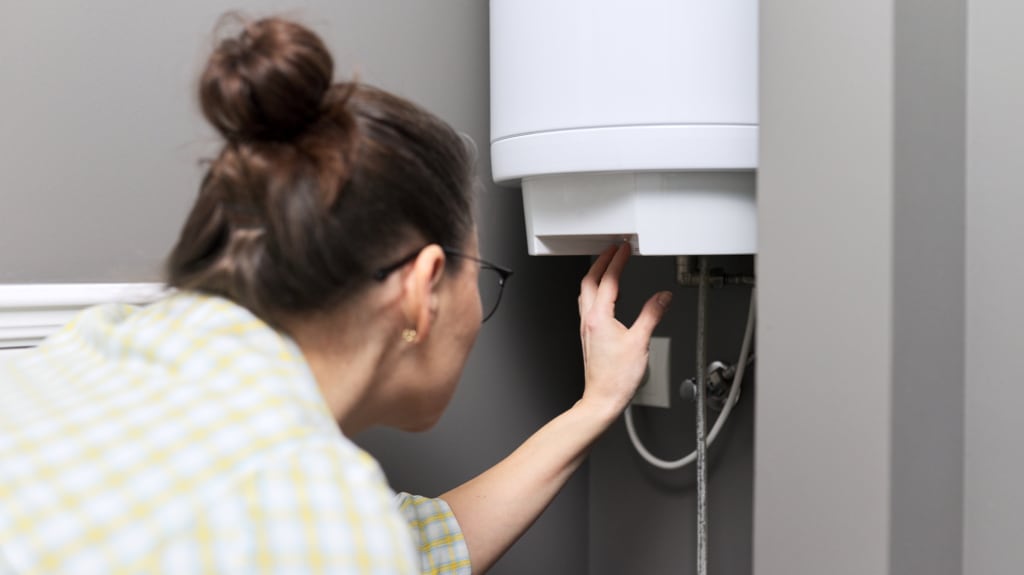 Woman's hand adjusts temperature of a water heater