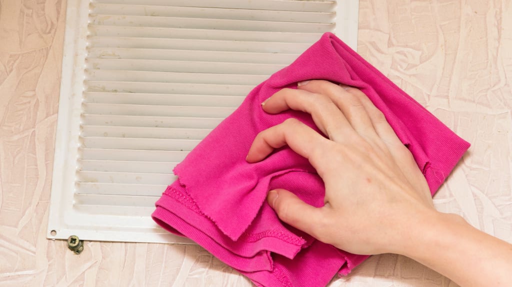 Hand cleaning vent grill with pink cloth