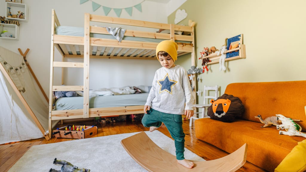 Petit garçon jouant avec une planche d'équilibre dans sa chambre
