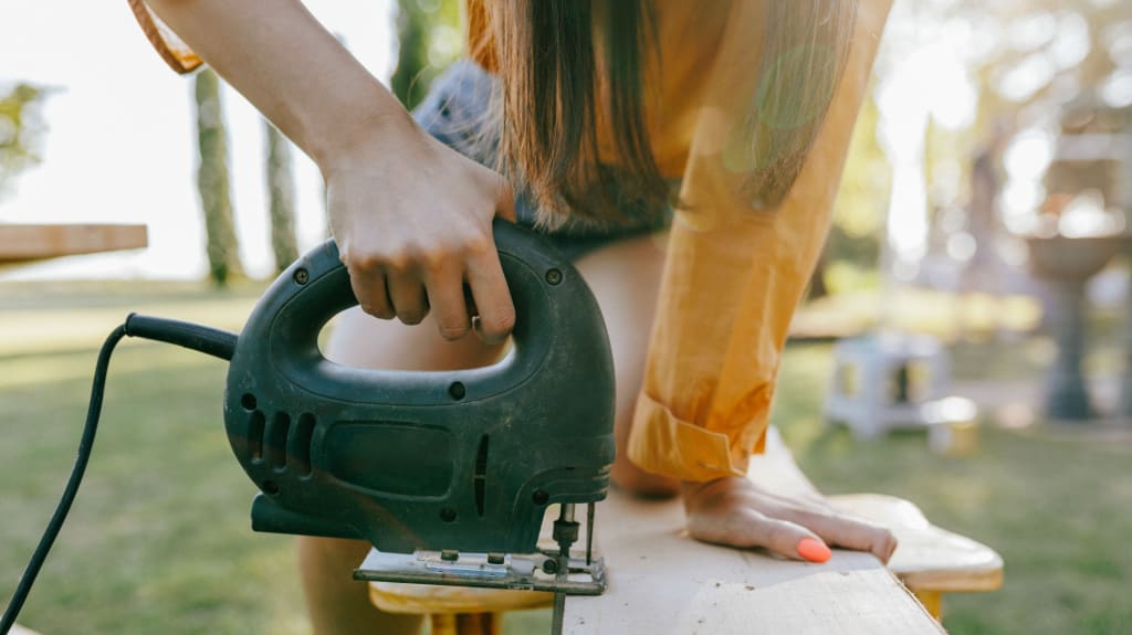 Close up of woman cutting wood with an electric jigsaw