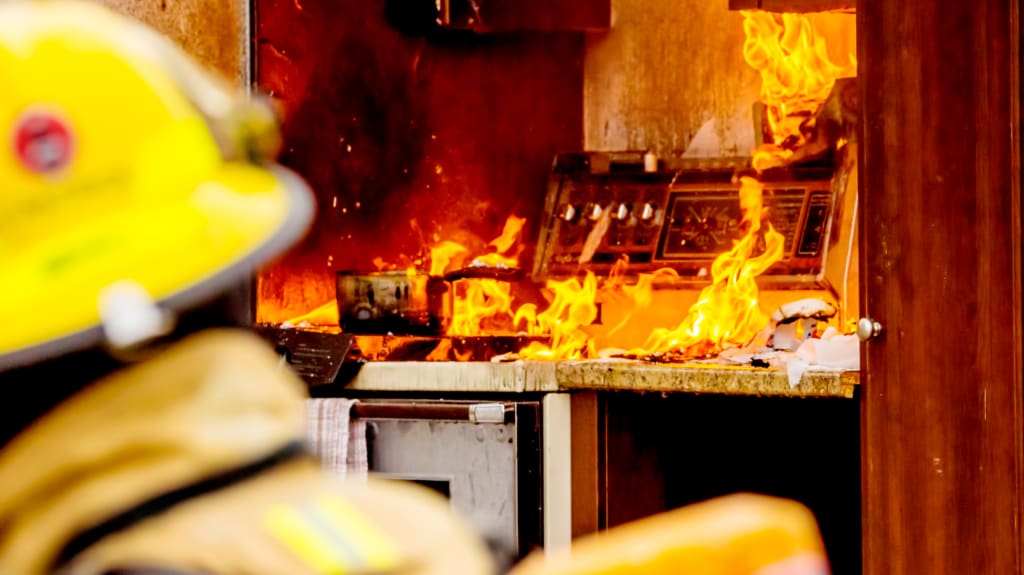 Pompier devant un feu et flammes sur une cuisinière