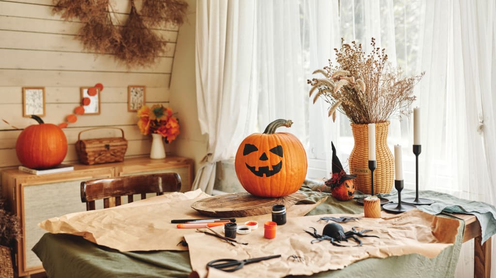 Table covered in paper, Halloween craft materials, and a pumpkin