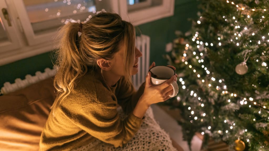 Femme buvant un thé devant un sapin de Noël