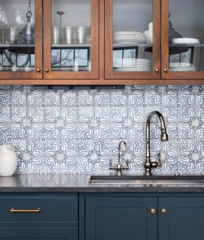 Dosseret carrelé à motifs entouré d’armoires bleues et en bois