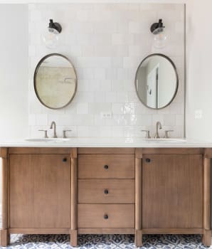 Salle de bain avec sol en carrelage à motif, meuble en bois naturel et dosseret en céramique Zellige