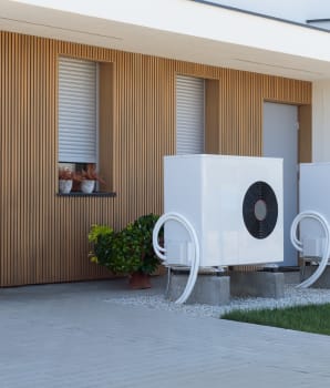 Paire de pompes à chaleur installées devant une maison contemporaine blanche avec bardage de bois vertical
