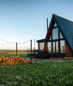 Petite habitation écologique de style chalet sur un terrain vaste avec toiture en tôle, cheminée et coin pour feux extérieurs