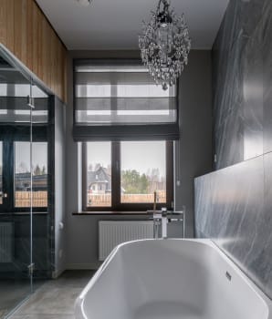 Salle de bain avec lustre majestueux et baignoire blanche contre un mur de marbre