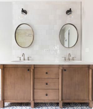 Bathroom with patterned tile floor, natural wood cabinetry and zellige ceramic backsplash 