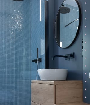 Monochrome bathroom in shades of blue with pale wood furniture 