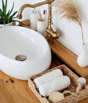 Vintage faucet, white washbasin and wicker basket with accessories 