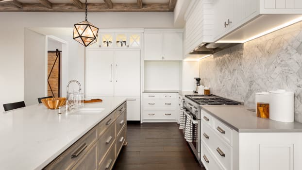 Cuisine blanche, grise et beige avec lampe suspendue et plancher de bois franc