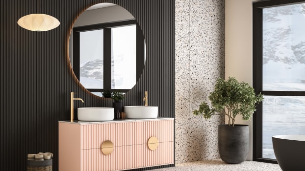 Salle de bain avec armoire rose, lavabo blanc, plante d’intérieur, murs en panneaux et sol en terrazzo