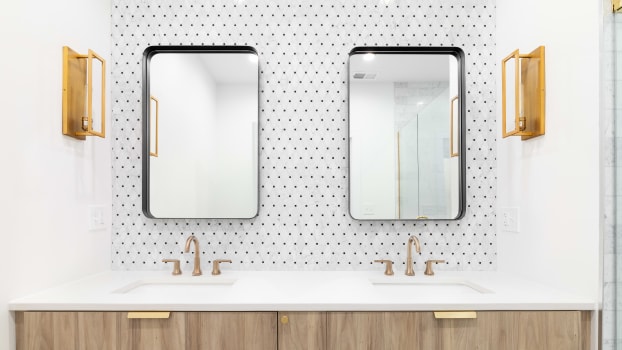 Salle de bain avec meuble en bois, appliques dorées et dosseret en carrelage