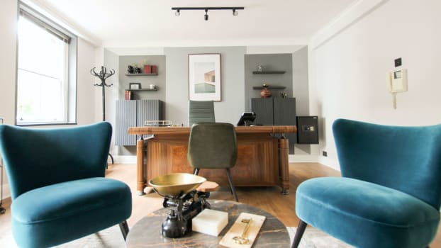 Home office with blue velvet chairs, wall shelves and storage units
